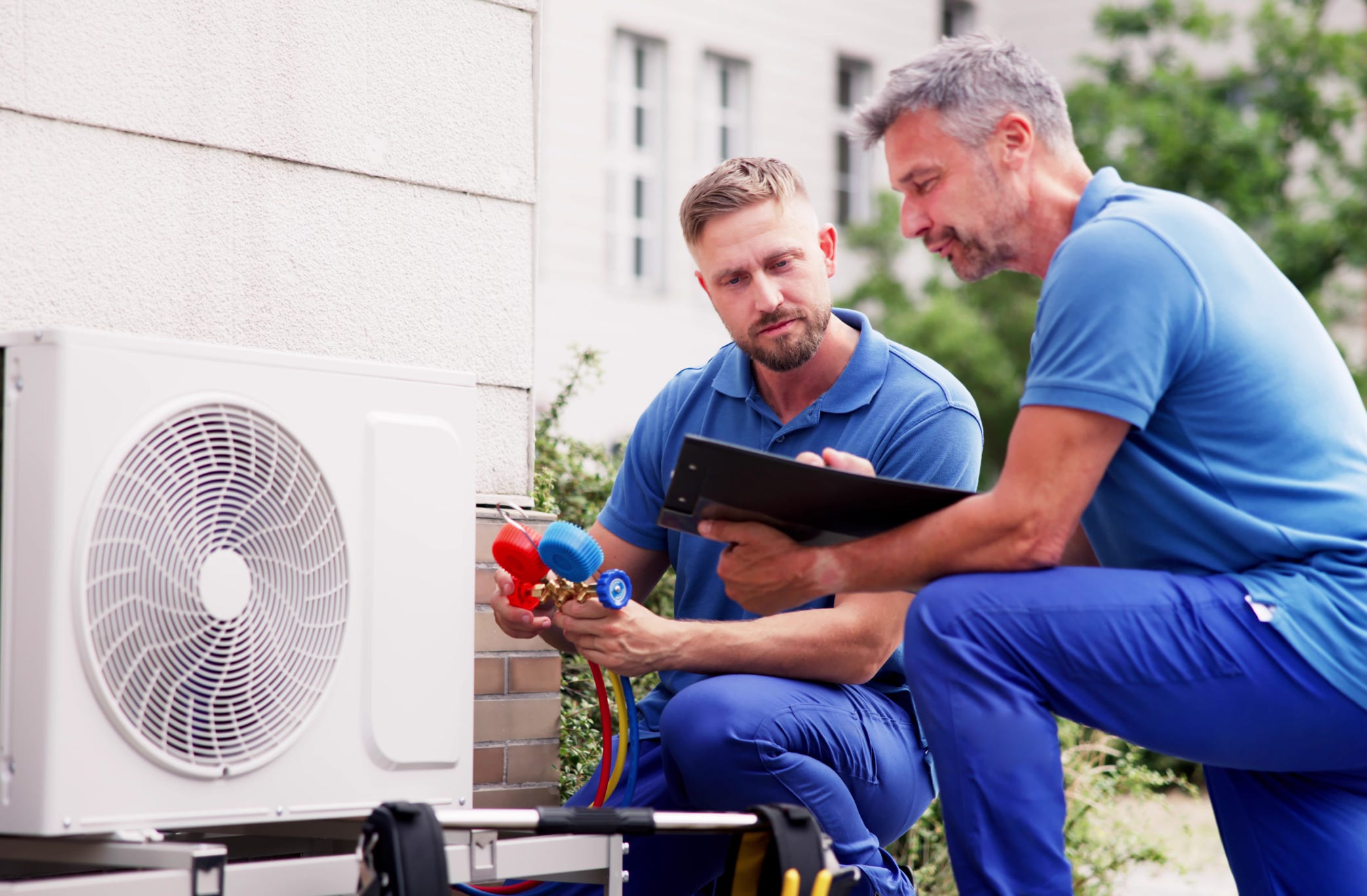 2 techniciens contrôlent le niveau de gaz d'une climatisation.