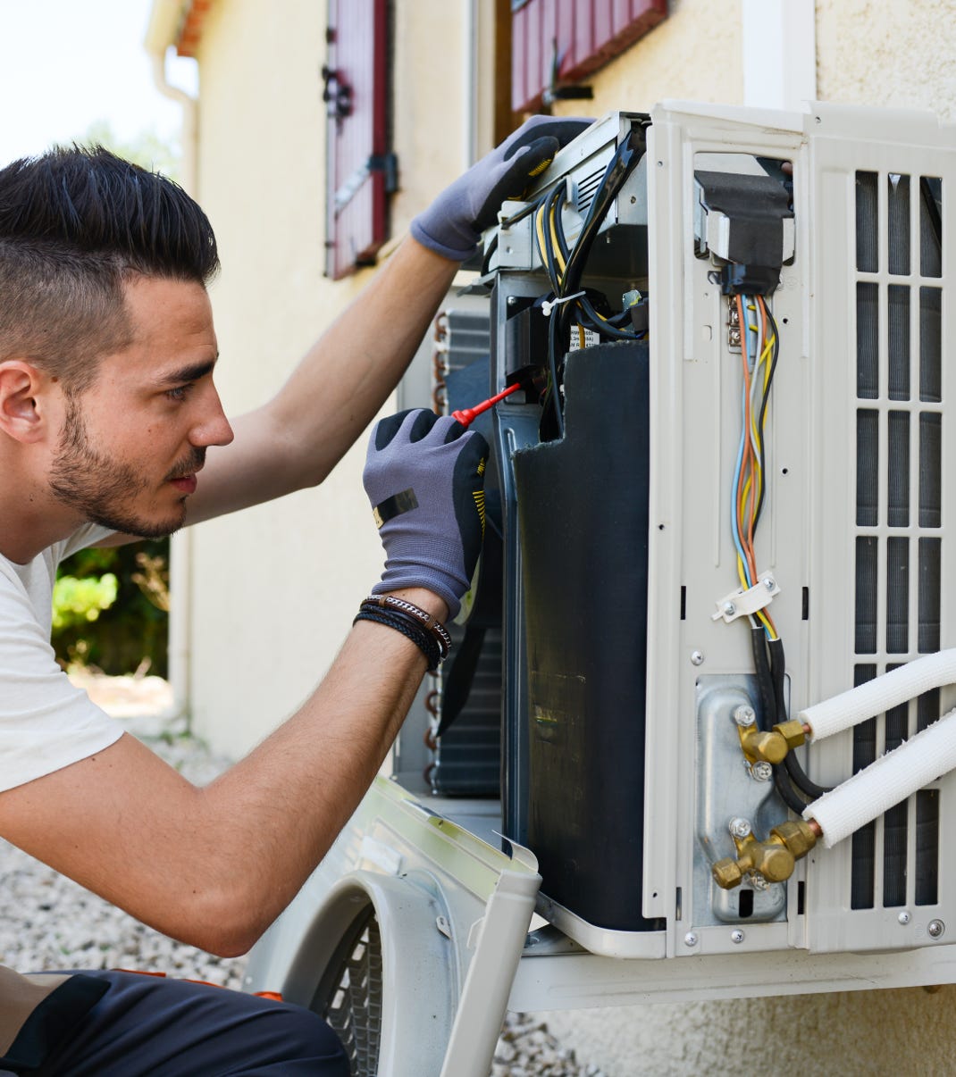 Un technicien intervient sur le circuit électrique d'une untité de climatisation extérieure